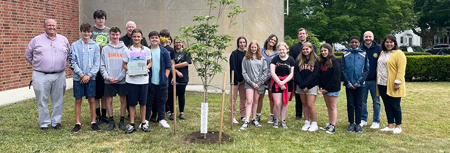 group of students and adults outside next to newly planted tree
