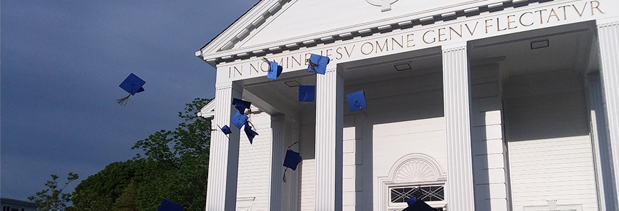 Graduation caps being thrown in the air outside of an official building