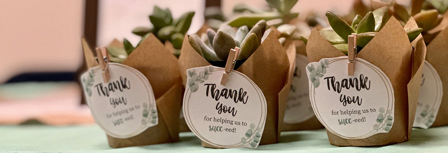 potted plants with a print out that reads Thank you for helping us to succ-eed!