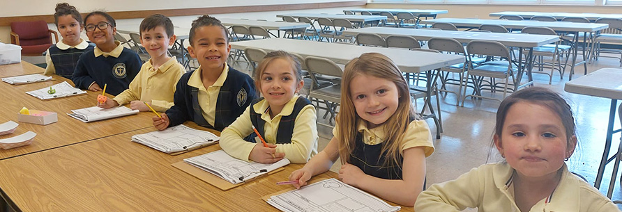 Row of happy elementary students in uniforms sitting in the classroom