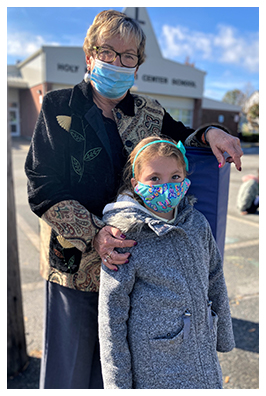 Adult and student posing outside for a pic while wearing face masks