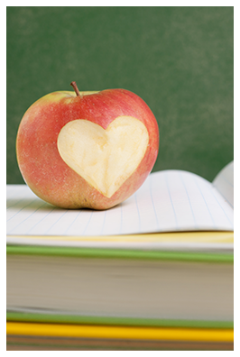 An apple with heart-shaped bite on top of books